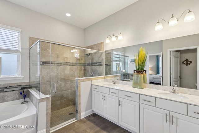 ensuite bathroom with a bath, a stall shower, double vanity, and a sink