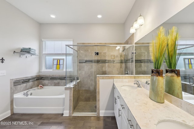 bathroom featuring baseboards, double vanity, a stall shower, a sink, and a garden tub