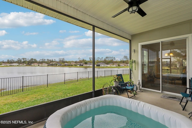 sunroom featuring a ceiling fan and a water view