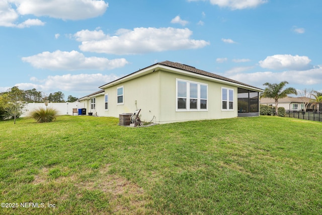 back of house featuring a lawn, a fenced backyard, and a sunroom