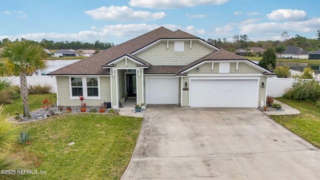 view of front of property with driveway, a front lawn, fence, roof with shingles, and an attached garage