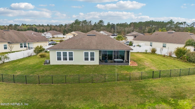 rear view of house with stucco siding, a fenced backyard, a yard, a residential view, and a shingled roof