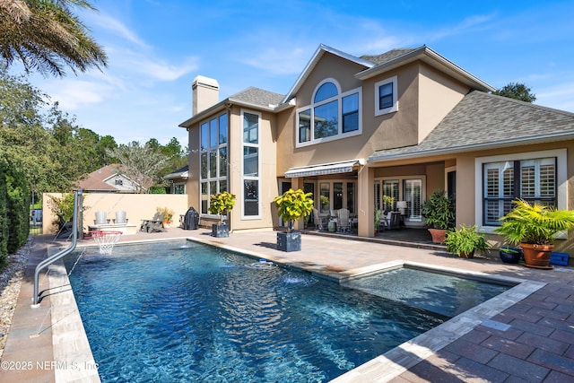 back of property with a fenced in pool, a patio area, and pool water feature