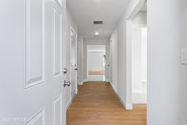 hall featuring light hardwood / wood-style flooring and a textured ceiling