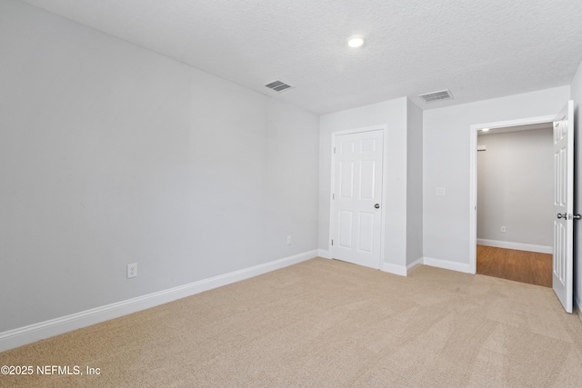 unfurnished bedroom featuring light carpet and a textured ceiling