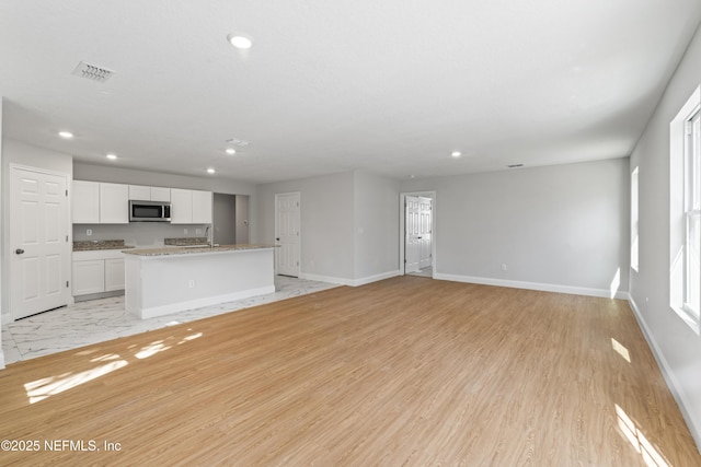 unfurnished living room with sink and light wood-type flooring