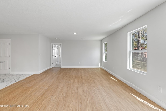 spare room with a textured ceiling and light hardwood / wood-style flooring