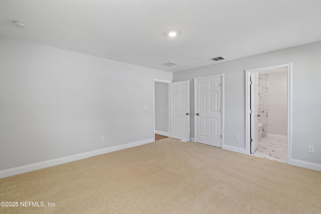 unfurnished bedroom with ensuite bathroom and light colored carpet