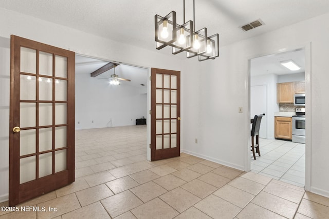 empty room with light tile patterned floors, ceiling fan with notable chandelier, and french doors