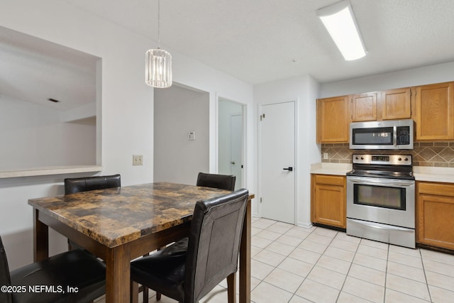 kitchen with pendant lighting, tasteful backsplash, light tile patterned flooring, and appliances with stainless steel finishes