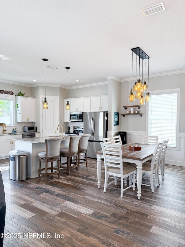 dining area with sink, dark wood-type flooring, and ornamental molding