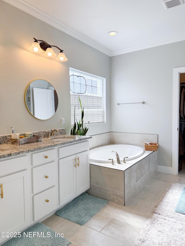 bathroom with tiled tub, crown molding, and vanity