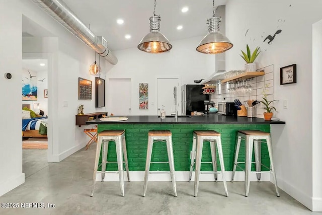 bar featuring stainless steel fridge, decorative light fixtures, and sink