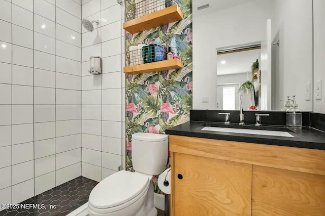 bathroom with vanity, a tile shower, and toilet