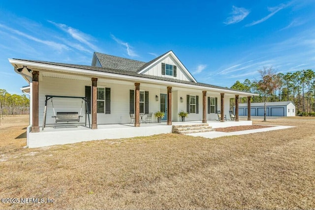 back of house with an outdoor structure, a yard, and covered porch