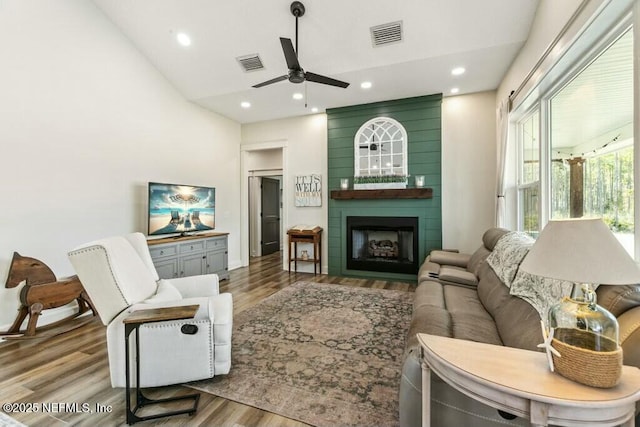 living room featuring hardwood / wood-style floors, vaulted ceiling, a large fireplace, and ceiling fan