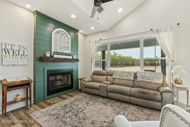 living room featuring hardwood / wood-style floors, vaulted ceiling, a fireplace, and ceiling fan