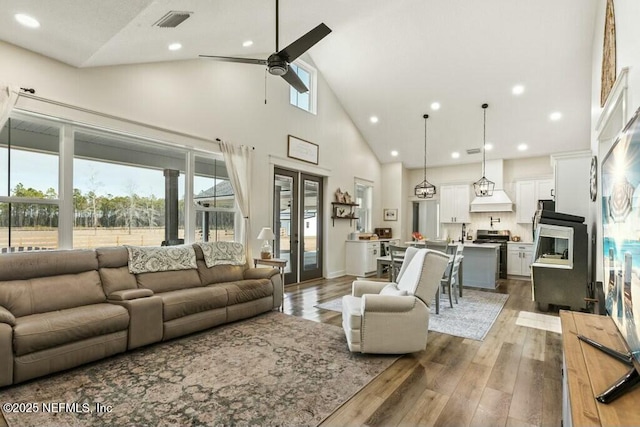 living room with dark wood-type flooring, ceiling fan, high vaulted ceiling, and french doors