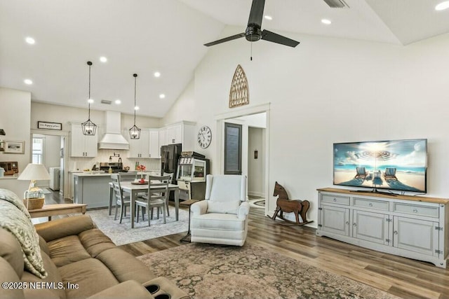 living room featuring ceiling fan, high vaulted ceiling, and light wood-type flooring