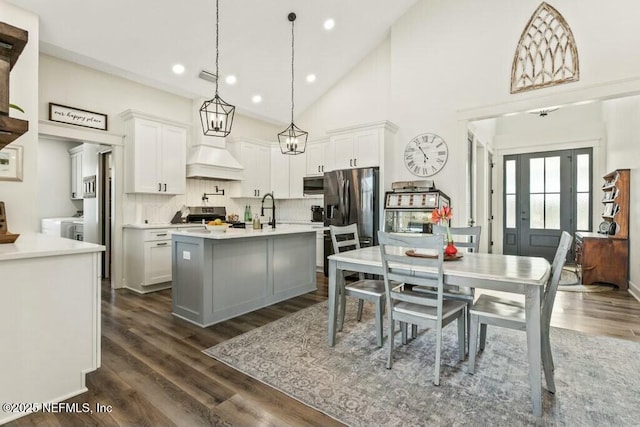 kitchen with pendant lighting, white cabinetry, stainless steel appliances, and an island with sink