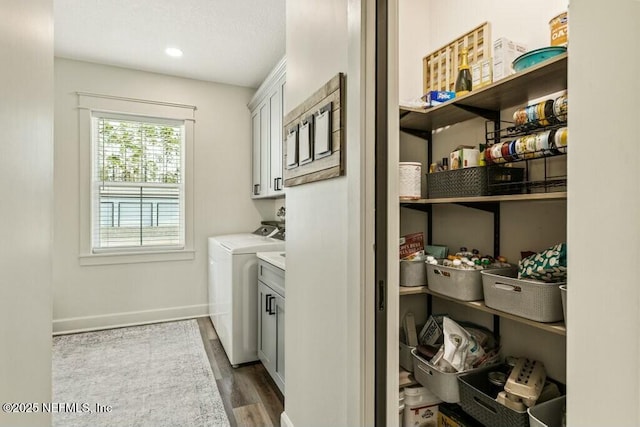 clothes washing area featuring cabinets, washer and dryer, and dark hardwood / wood-style flooring