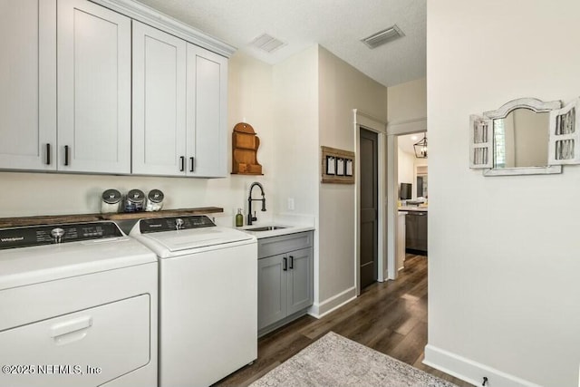 laundry room with sink, dark wood-type flooring, washing machine and dryer, and cabinets