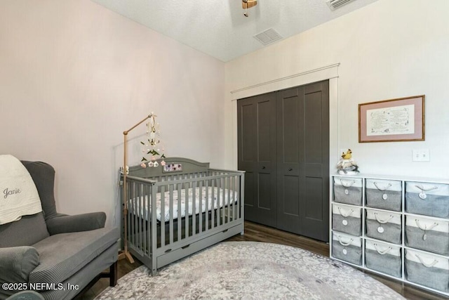 bedroom featuring a closet, a crib, and dark hardwood / wood-style floors