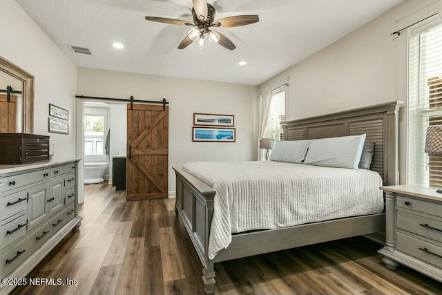 bedroom featuring dark hardwood / wood-style floors, a barn door, and multiple windows