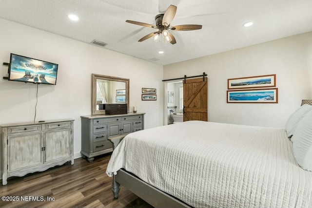 bedroom featuring dark wood-type flooring, ceiling fan, and a barn door