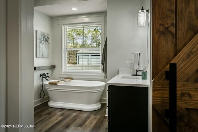 bathroom featuring vanity, hardwood / wood-style floors, and a bathtub