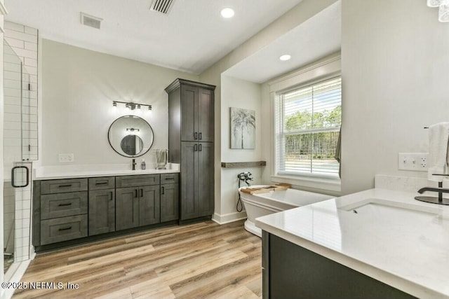 bathroom with vanity, independent shower and bath, and hardwood / wood-style floors