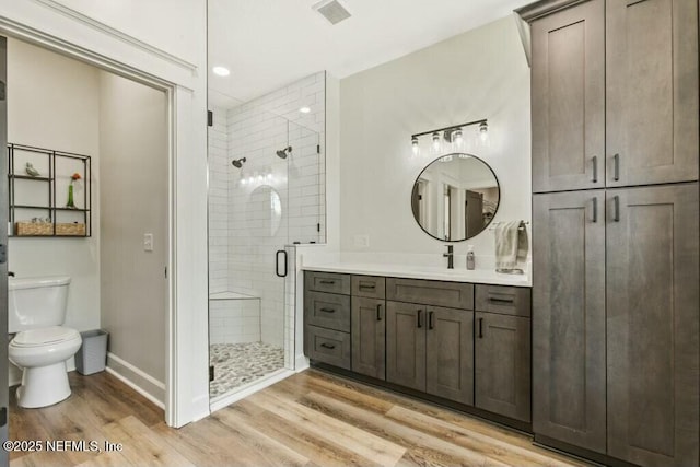 bathroom featuring vanity, toilet, an enclosed shower, and hardwood / wood-style floors