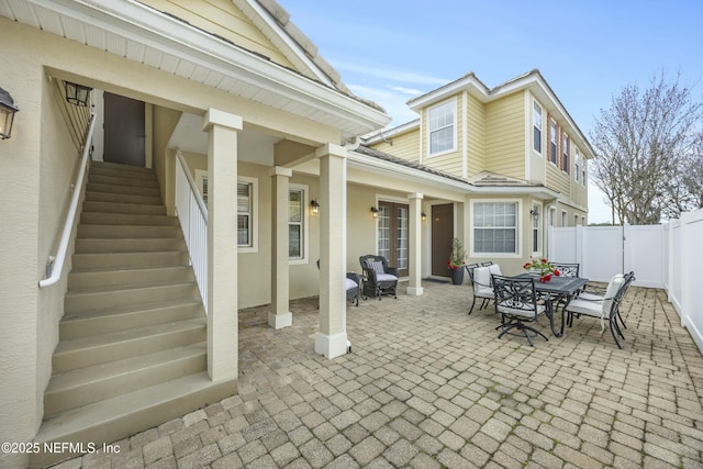 view of patio / terrace with stairs, outdoor dining area, and fence