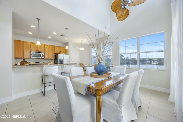 dining room with light tile patterned floors, a ceiling fan, baseboards, a high ceiling, and recessed lighting