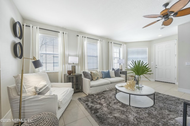 living area with light tile patterned floors, baseboards, a wealth of natural light, and a ceiling fan