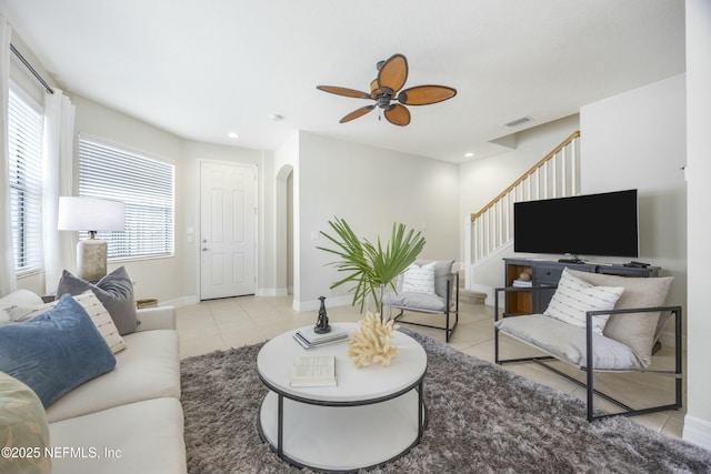 tiled living area featuring visible vents, recessed lighting, stairway, arched walkways, and baseboards