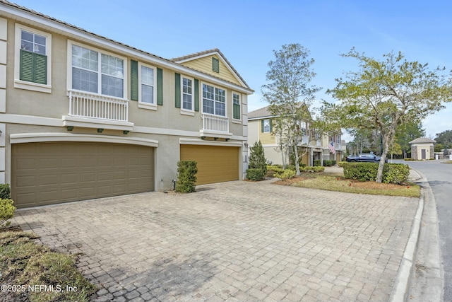 multi unit property with decorative driveway, a garage, and stucco siding