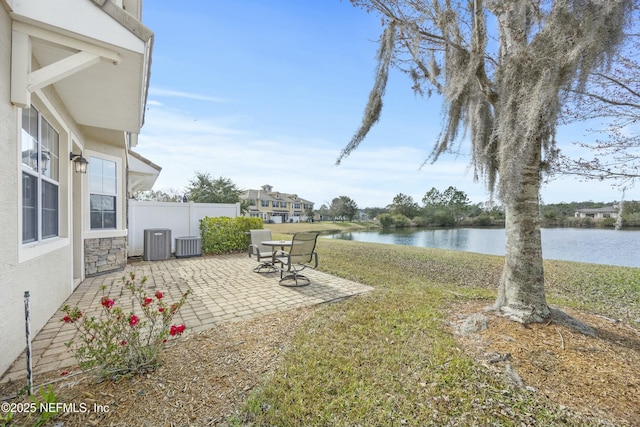 view of yard featuring central AC unit, fence, a patio, and a water view