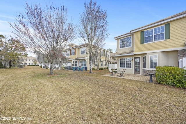 back of house with a patio, a yard, stone siding, and a residential view