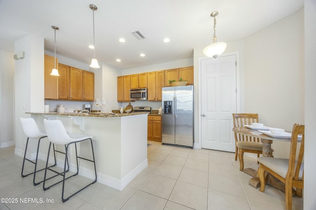 kitchen featuring visible vents, decorative light fixtures, stone counters, a peninsula, and stainless steel appliances