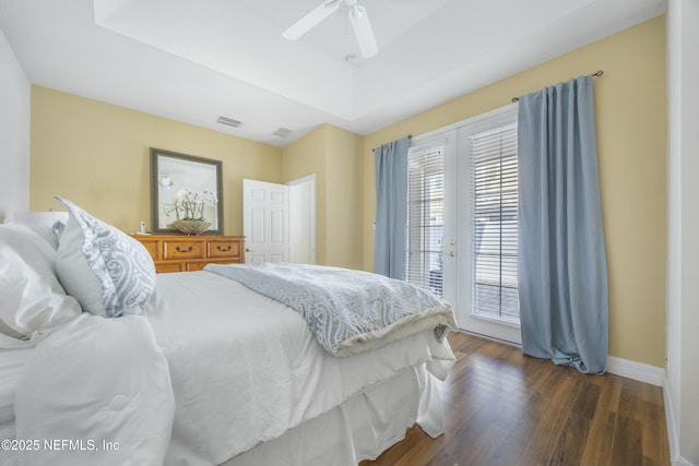 bedroom featuring visible vents, access to outside, wood finished floors, baseboards, and a raised ceiling