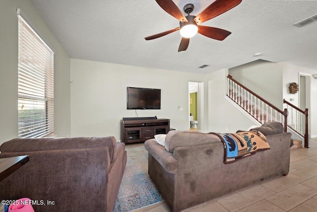 living room with ceiling fan, light tile patterned floors, and a textured ceiling