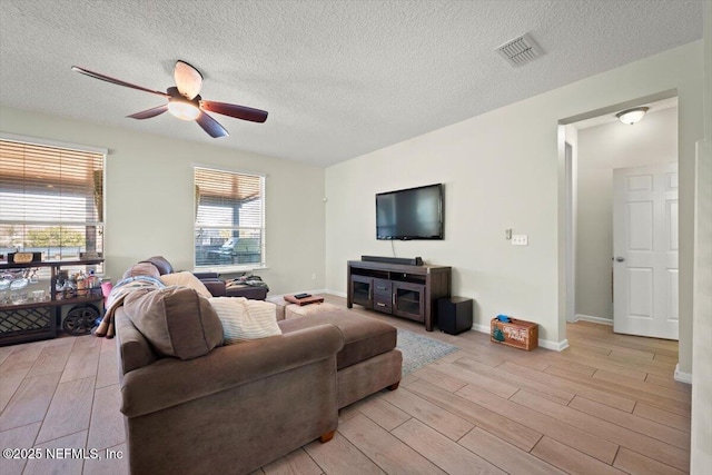 living room with ceiling fan, a textured ceiling, and light hardwood / wood-style floors