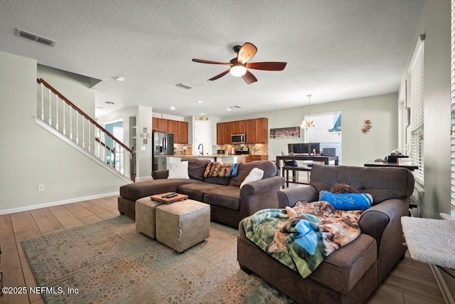 living room featuring ceiling fan, sink, hardwood / wood-style floors, and a textured ceiling