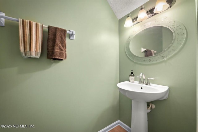 bathroom with lofted ceiling, sink, and a textured ceiling