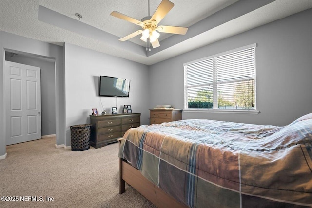 carpeted bedroom featuring ceiling fan, a textured ceiling, and a tray ceiling