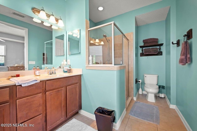 bathroom featuring tile patterned flooring, vanity, toilet, and walk in shower