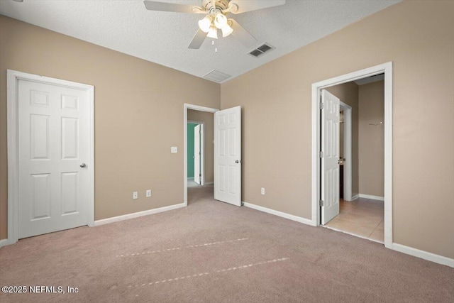 unfurnished bedroom with ceiling fan, light colored carpet, and a textured ceiling