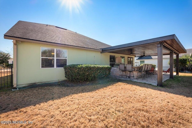 rear view of property featuring ceiling fan, a yard, and a patio