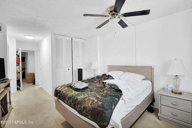 carpeted bedroom with ceiling fan, a textured ceiling, and a closet